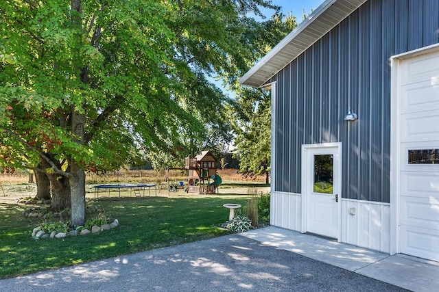 view of yard with a playground, a garage, and a trampoline