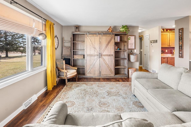 living room with a barn door and dark wood-type flooring