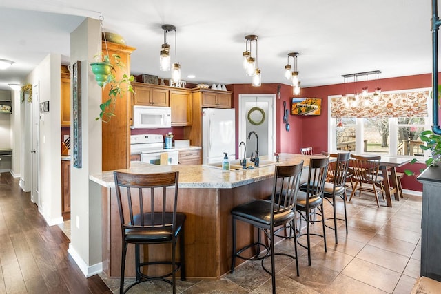 kitchen with pendant lighting, white appliances, sink, dark hardwood / wood-style floors, and a notable chandelier