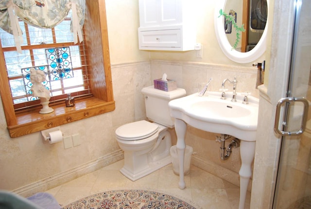 bathroom with toilet, tile walls, and a healthy amount of sunlight