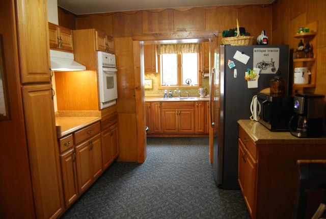 kitchen featuring wood walls, sink, and appliances with stainless steel finishes