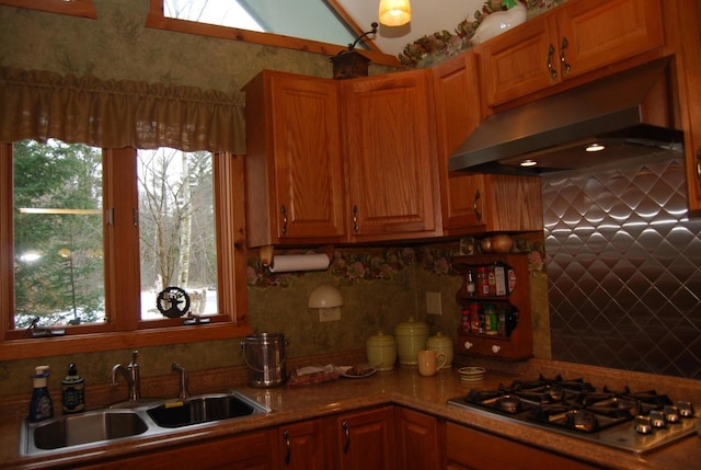 kitchen featuring vaulted ceiling with skylight, decorative backsplash, sink, and stainless steel gas cooktop