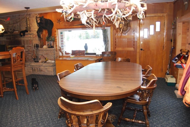 dining room featuring wood walls, dark colored carpet, and a notable chandelier