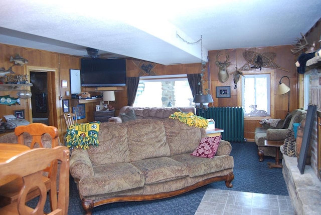 living room with radiator, wood walls, and ceiling fan