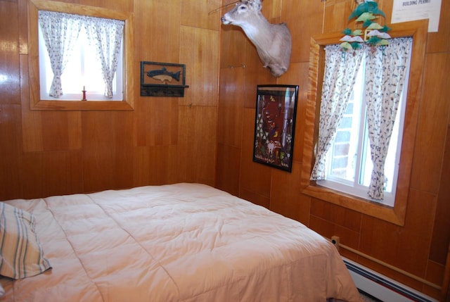 bedroom featuring multiple windows, wood walls, and a baseboard radiator