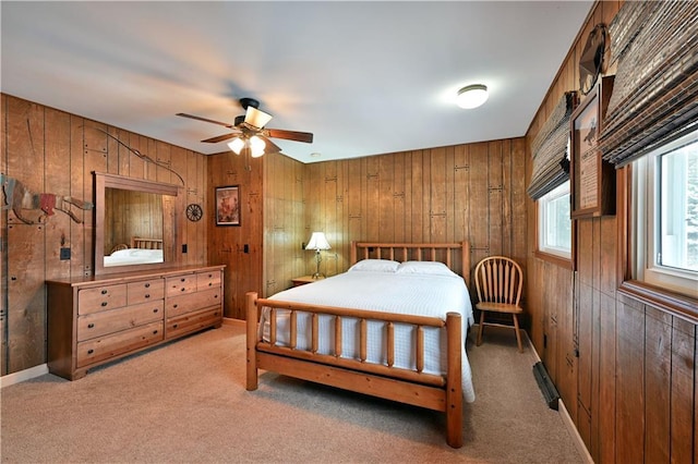 bedroom with ceiling fan, wood walls, and light colored carpet