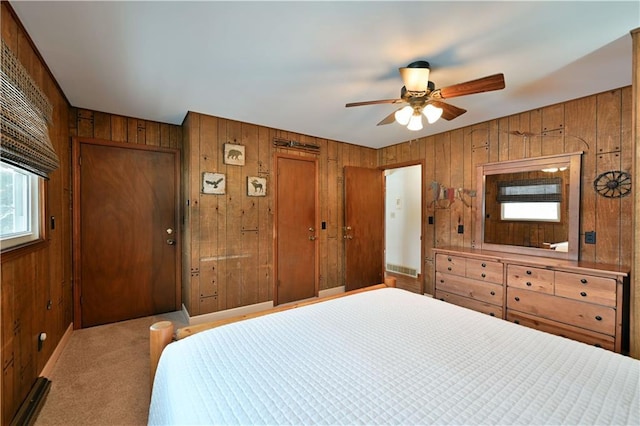 bedroom featuring ceiling fan, wood walls, and light colored carpet