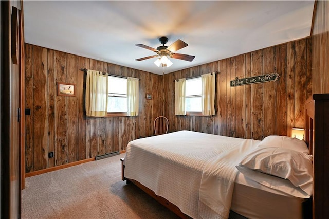 carpeted bedroom with ceiling fan, wood walls, and baseboard heating