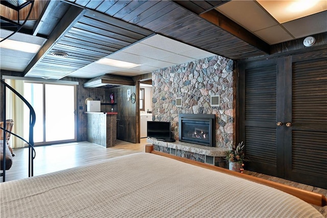 bedroom featuring a fireplace, light hardwood / wood-style flooring, and wood walls