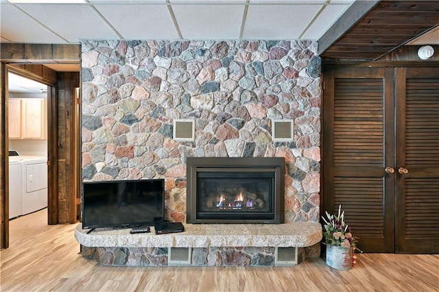 interior details with a drop ceiling, independent washer and dryer, wood-type flooring, and a fireplace