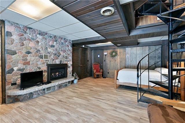 bedroom with wood walls, a fireplace, and hardwood / wood-style flooring