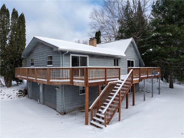 snow covered house featuring a garage and a wooden deck