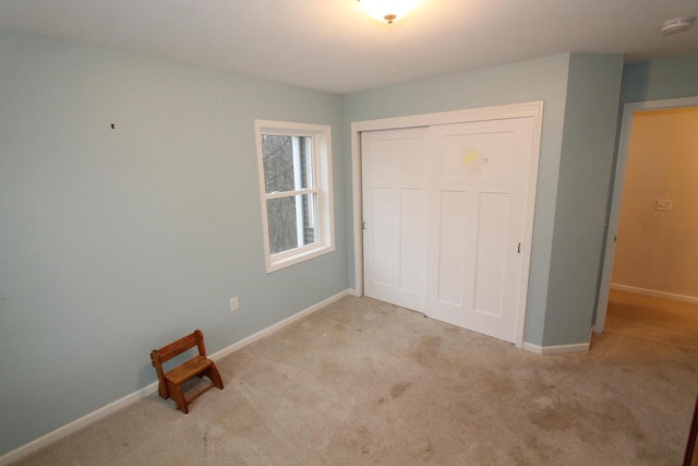 unfurnished bedroom featuring light carpet and a closet