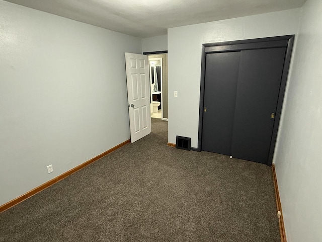 unfurnished bedroom with dark carpet and a closet