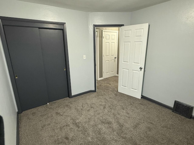 unfurnished bedroom featuring dark colored carpet and a closet