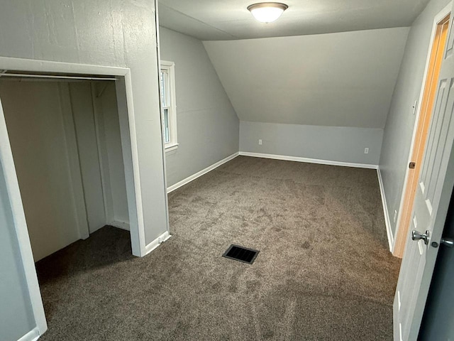 bonus room with lofted ceiling and dark colored carpet