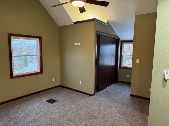 unfurnished bedroom featuring ceiling fan, multiple windows, and vaulted ceiling