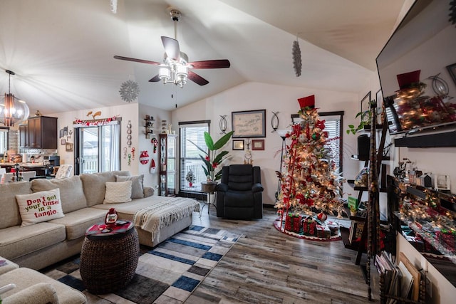 living room with ceiling fan with notable chandelier, dark hardwood / wood-style flooring, and lofted ceiling