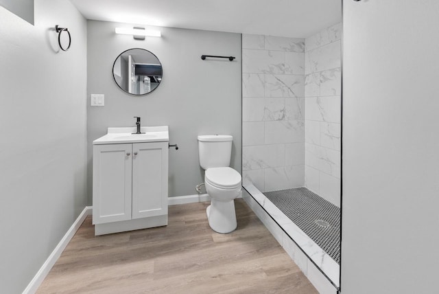 bathroom featuring tiled shower, hardwood / wood-style floors, vanity, and toilet