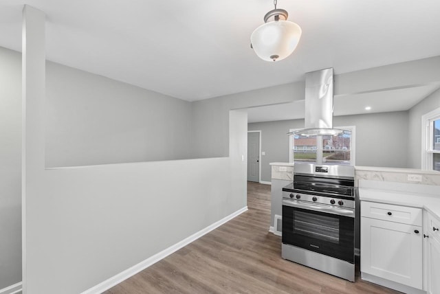 kitchen featuring light hardwood / wood-style flooring, stainless steel stove, white cabinetry, and island range hood