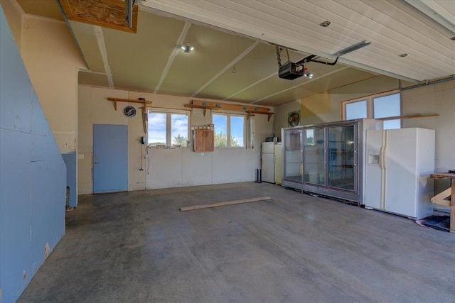 garage featuring white fridge with ice dispenser, a garage door opener, and white refrigerator