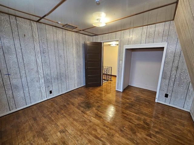 unfurnished room featuring wood walls and dark hardwood / wood-style floors