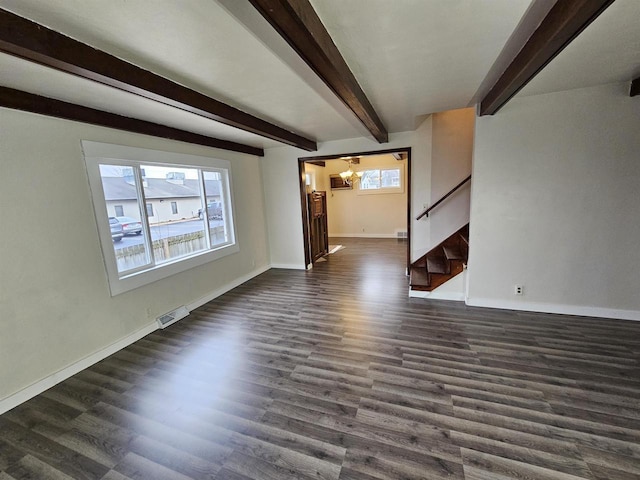 unfurnished living room featuring dark wood-type flooring, an inviting chandelier, and plenty of natural light