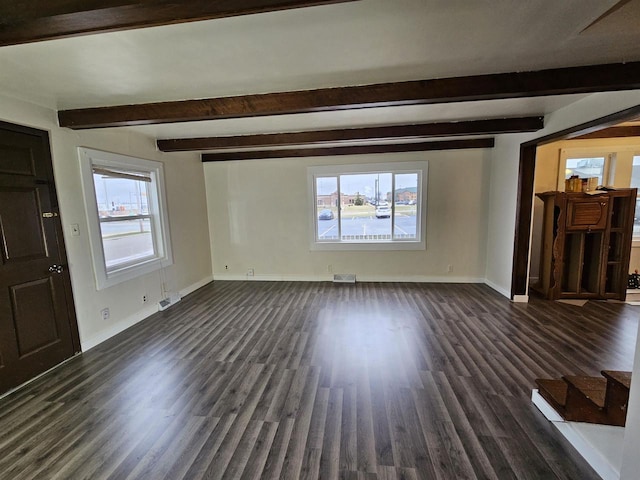 unfurnished living room with beamed ceiling, a wealth of natural light, and dark hardwood / wood-style flooring