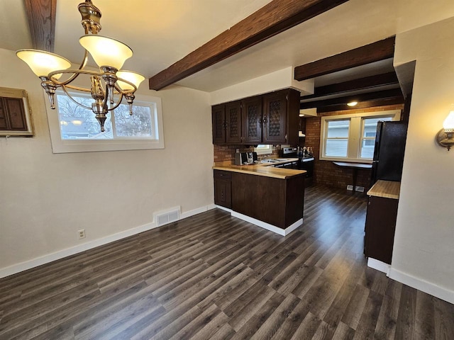 kitchen with black refrigerator, a wealth of natural light, dark brown cabinets, and beamed ceiling