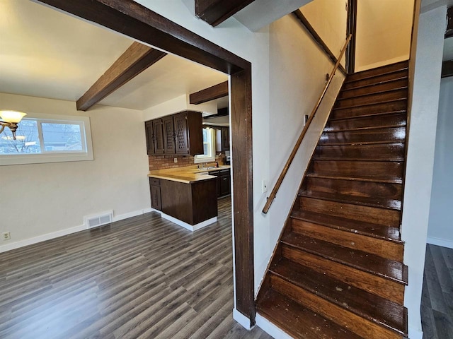 stairs with sink, hardwood / wood-style floors, a wealth of natural light, and beamed ceiling