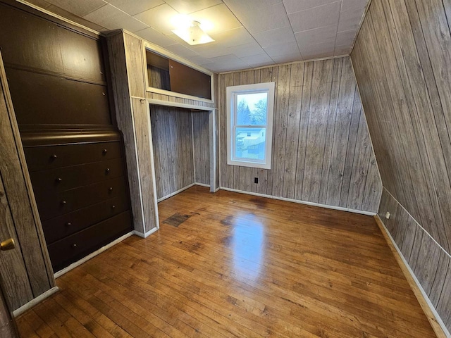 unfurnished bedroom with hardwood / wood-style flooring, wood walls, and a closet