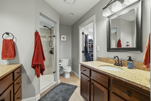 bathroom featuring toilet, hardwood / wood-style floors, vanity, and a tile shower