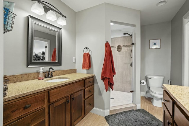 bathroom with wood-type flooring, vanity, and a tile shower