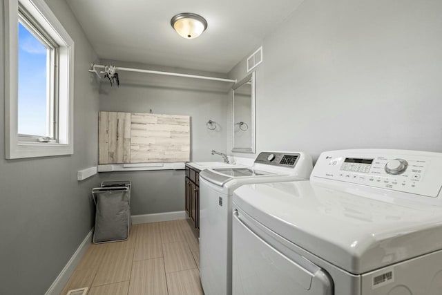 clothes washing area with sink, cabinets, and independent washer and dryer