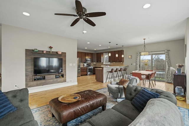 living room with ceiling fan and light hardwood / wood-style flooring