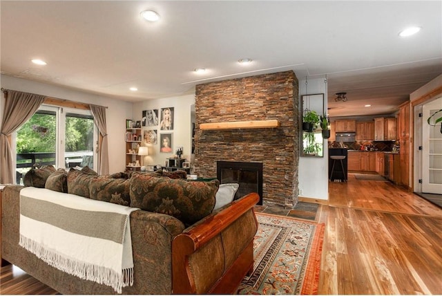 living room featuring a stone fireplace and light hardwood / wood-style flooring