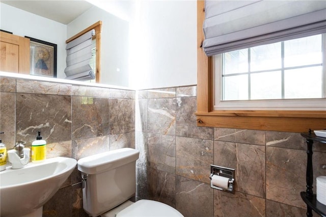 bathroom featuring sink, tile walls, and toilet