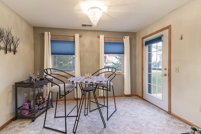 dining area featuring light carpet and a notable chandelier