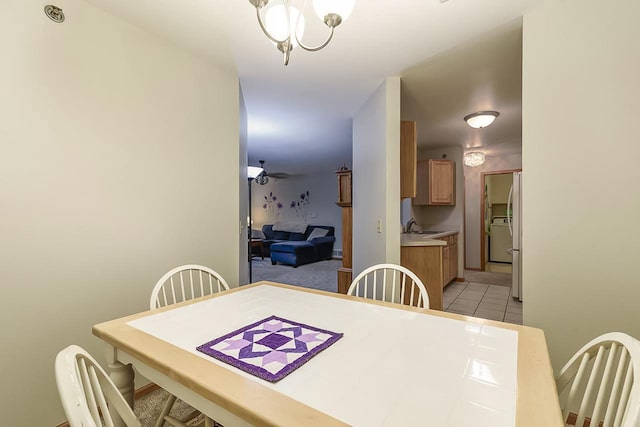 tiled dining area featuring sink and ceiling fan with notable chandelier