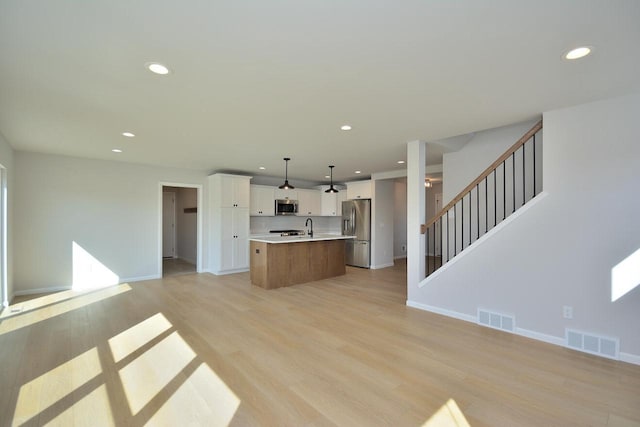 929 5 Mile Rd, Racine, WI 53402 - kitchen featuring appliances with stainless steel finishes, open floor plan, light countertops, a center island with sink, and white cabinetry