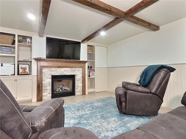 living room featuring beam ceiling, wooden walls, built in features, and a brick fireplace