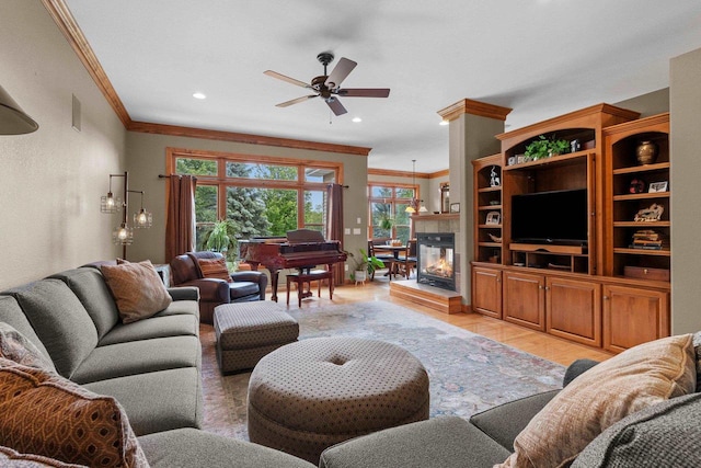 living room featuring light hardwood / wood-style floors, ceiling fan, ornamental molding, and a tiled fireplace