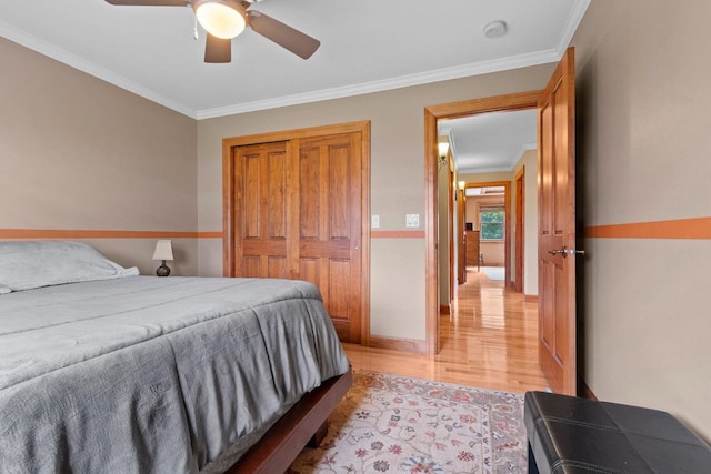 bedroom featuring ceiling fan, light hardwood / wood-style floors, ornamental molding, and a closet