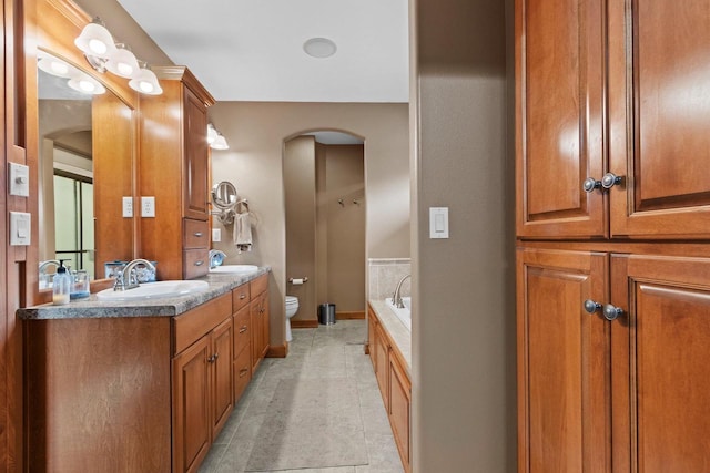 bathroom featuring tile patterned flooring, vanity, a tub to relax in, and toilet