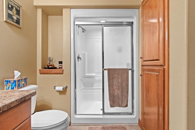 bathroom with toilet, vanity, tile patterned floors, and walk in shower