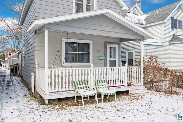 snow covered property entrance featuring a porch