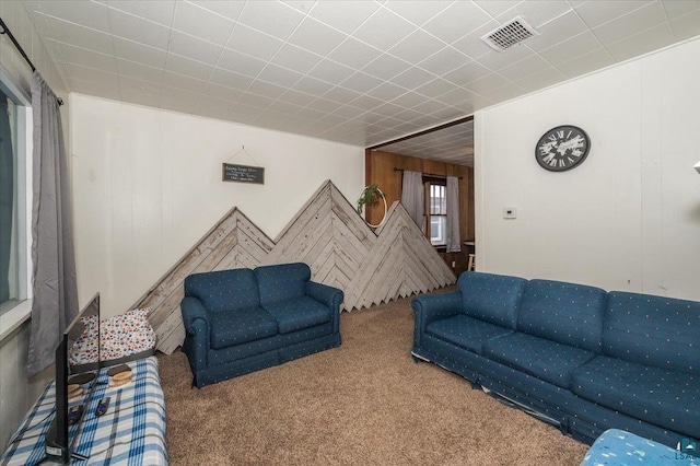 carpeted living room with wood walls