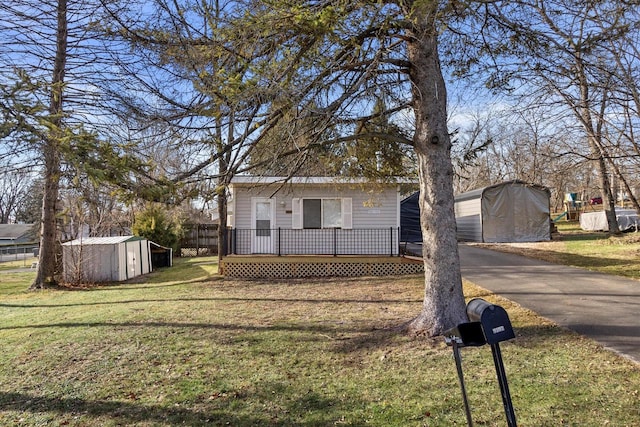 view of front of property with a storage unit, a deck, and a front lawn