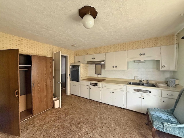 637 N Wright Rd, Janesville, WI 53546 - kitchen with black appliances, a textured ceiling, under cabinet range hood, dark carpet, and light countertops