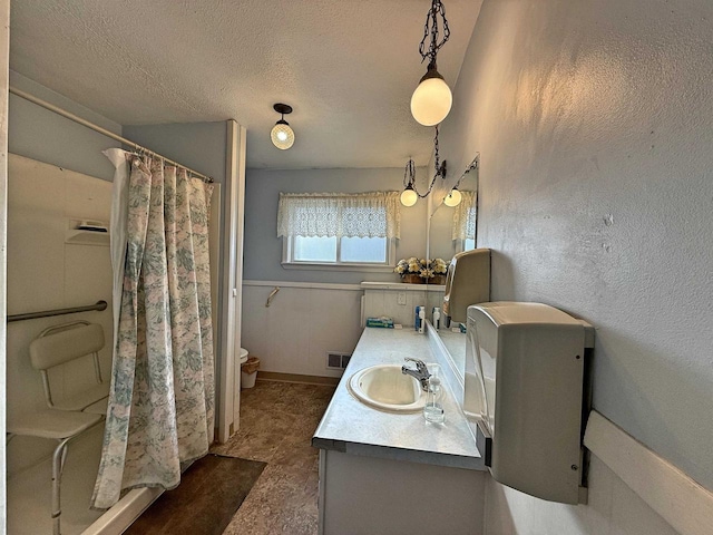 bathroom with curtained shower, vanity, a textured ceiling, and toilet